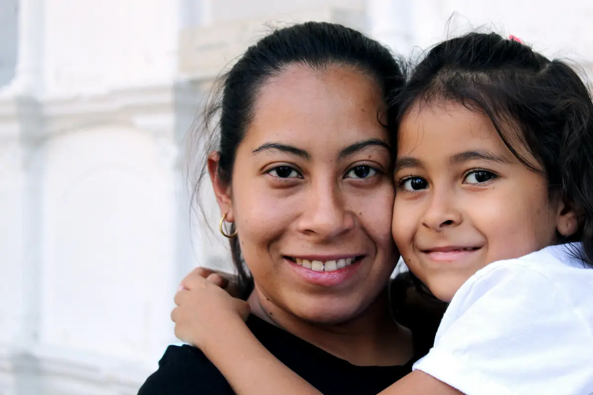 A smiling mother hugging her young daughter